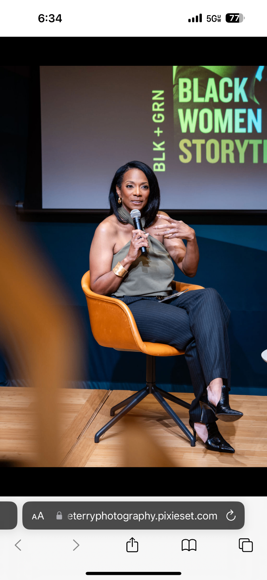 Robin moderating a live panel discussion, seated on stage holding a microphone